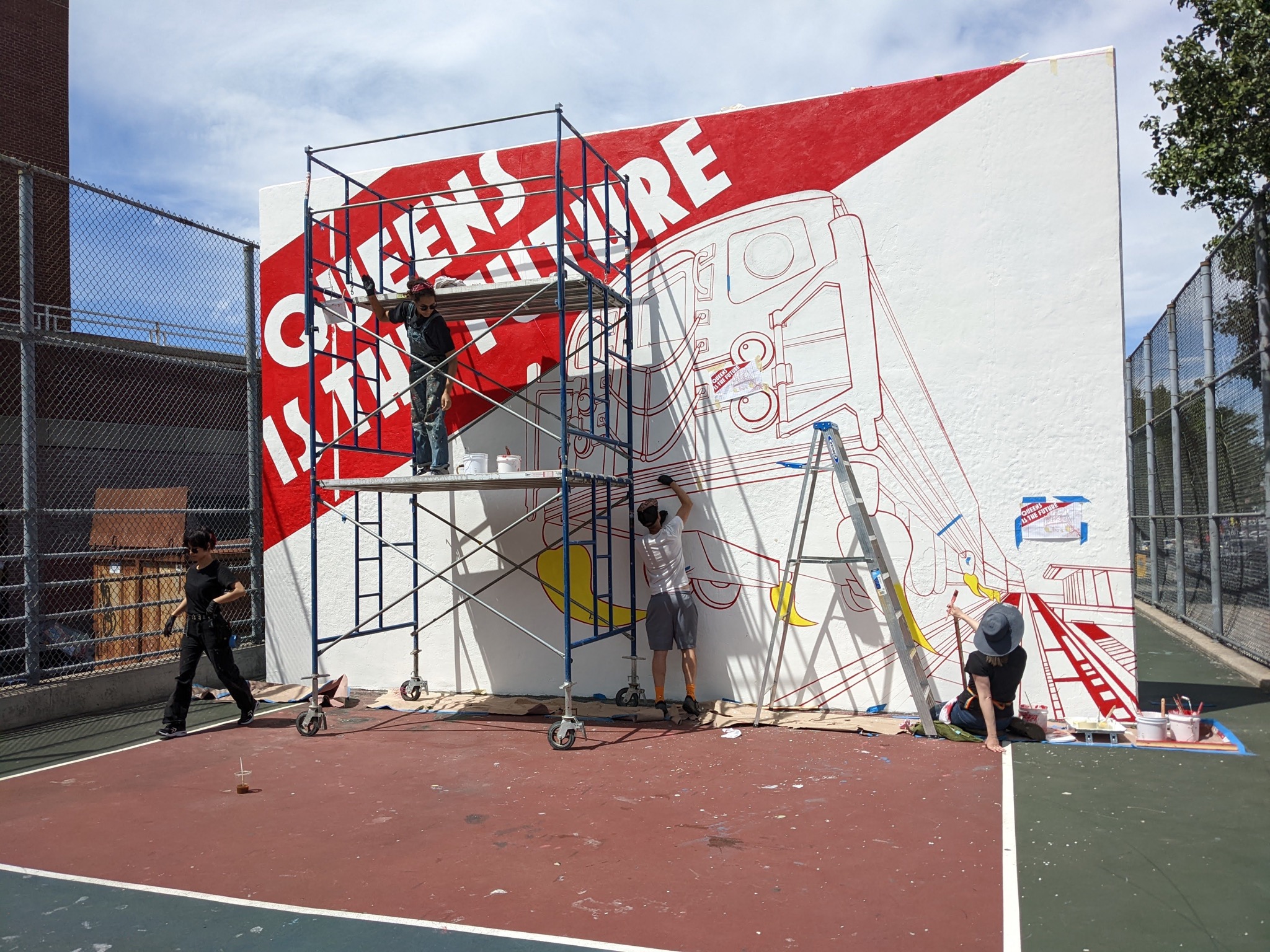 The QUEENS IS THE FUTURE mural being restored. Four painters at work with scaffolding and tools.